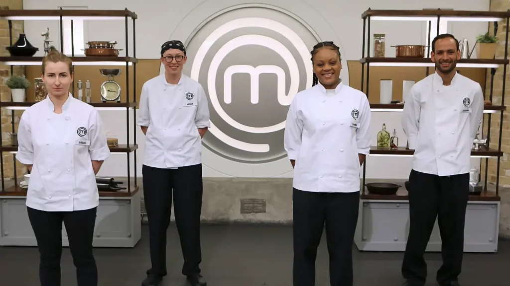 Four contestants from "MasterChef UK" pose in a kitchen setting with decorative shelving units on either side. From left to right: A woman with long blonde hair, wearing a chef's jacket with a name tag reading "DIANA"; a young man with glasses and wearing a black cap, in a chef's jacket with a name tag reading "MICKEY"; a smiling woman with braided hair, wearing a chef's jacket; and a man with short dark hair and a beard, wearing a chef's jacket with a name tag reading "LIAM". All are dressed in white chef's jackets and stand proudly in front of the large "MasterChef" logo.